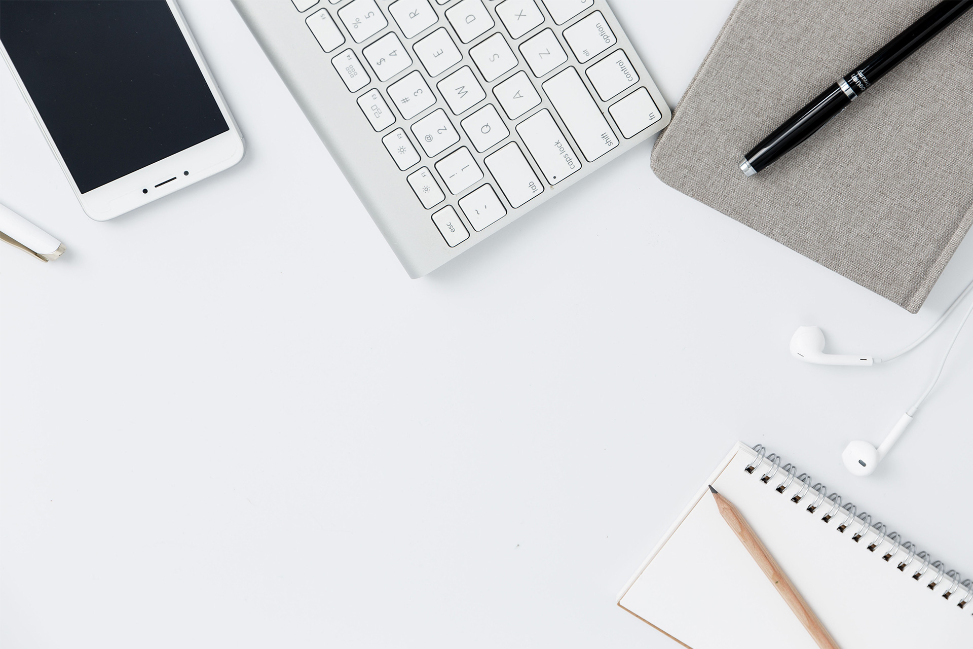 This is an image of an office desk with computer, cell phone, paper, and pens.